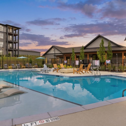Accent Springs pool with in-water loungers, poolside chairs, umbrellas and a fire pit next to the clubhouse