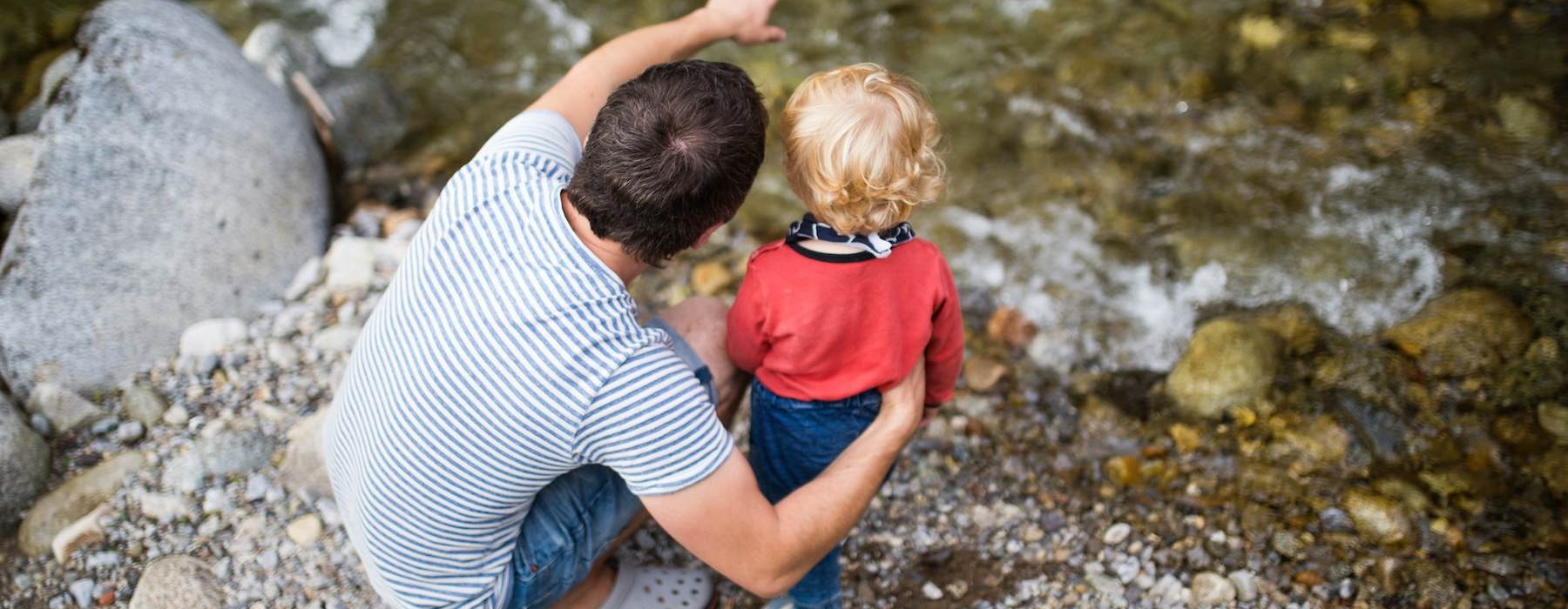a man and a child playing in a rocky river bed