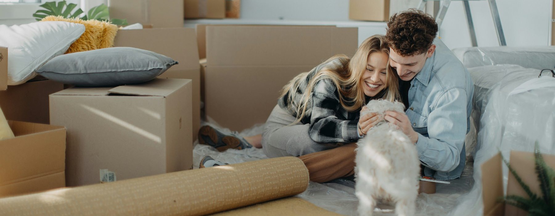 a man and a woman playing with a cat on a couch